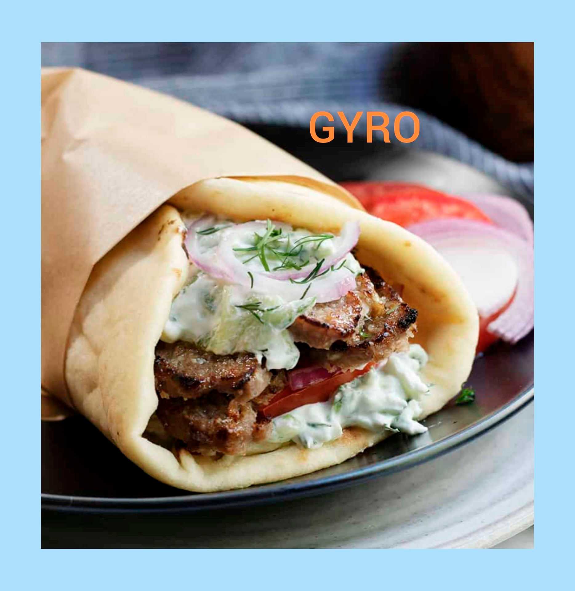 Gyro with tzatziki sauce, onions, and tomatoes wrapped in pita on a black plate.