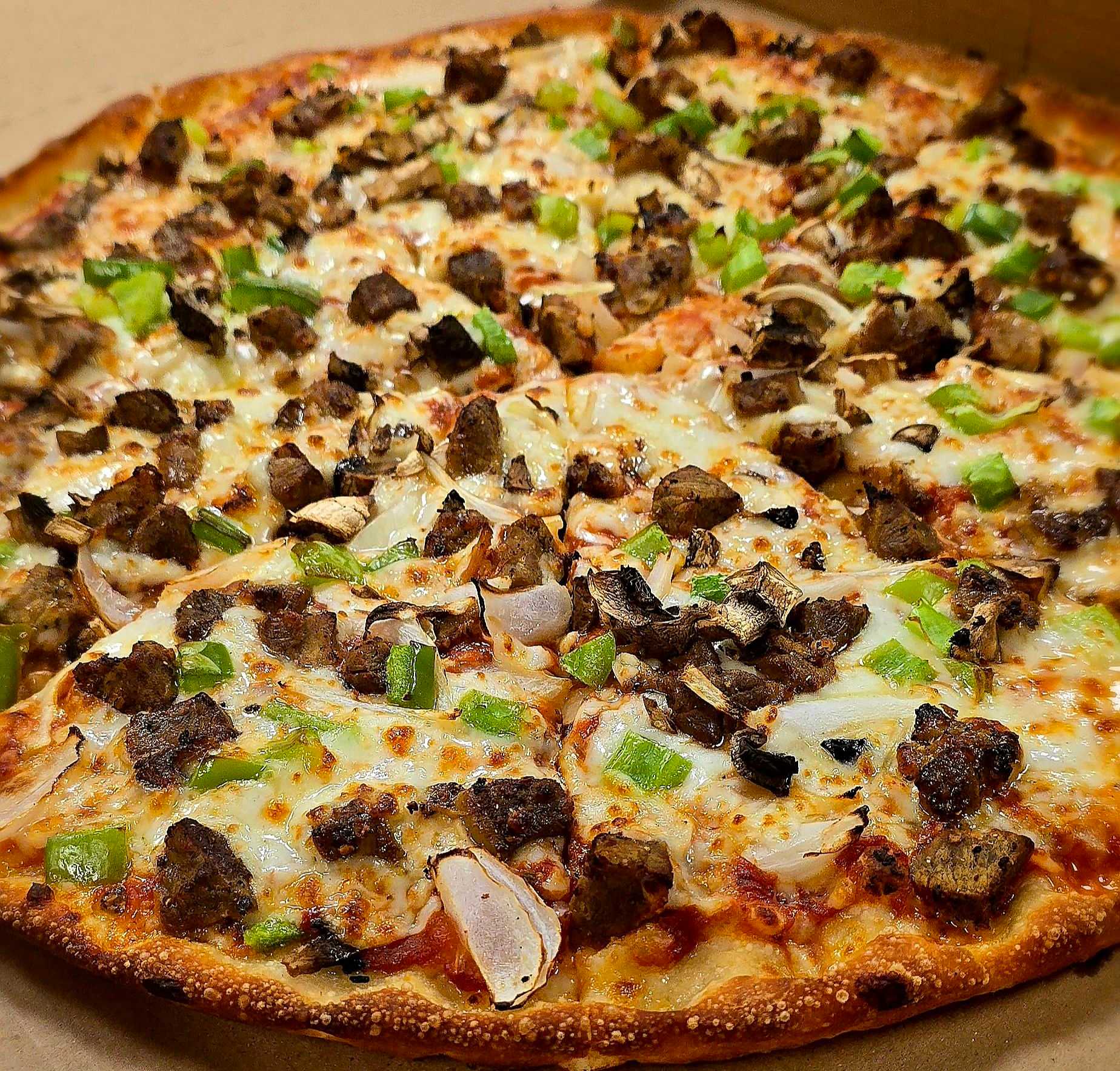 Close-up of a pizza topped with green peppers, onions, mushrooms, and sausage.